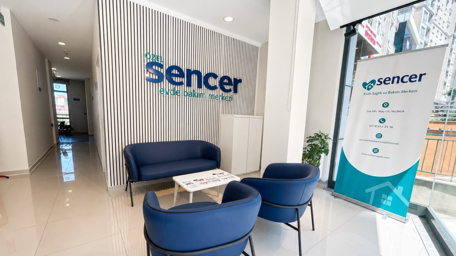 Merkezin bekleme alanı: duvarda Sencer logosu, lacivert koltuklar ve sehpa